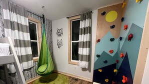 A room with a bunk bed, a green hanging chair, a climbing wall, and a wooden floor. - Magical Northern Michigan Cottage with Hot Tub (Bear Lake)