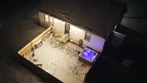 A model of a house with a snow-covered patio, a hot tub, and a staircase leading to the entrance. - Magical Northern Michigan Cottage with Hot Tub (Bear Lake)