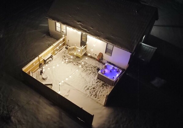 Een model van een huis met een sneeuwbedekt terras, een jacuzzi en een trap naar de ingang.