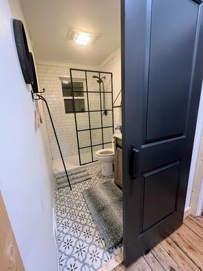 Een badkamer met een douchecabine, toilet en vloertegels met een patroon.