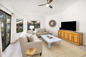 A spacious living room with a sofa, coffee table, and TV stand.