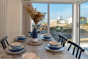Dining table seating six with sea views through the patio doors, pet-friendly beachside holiday bungalow in Rhosneigr, Anglesey - Morawelon: 100m from the beach in Rhosneigr (Rhosneigr)