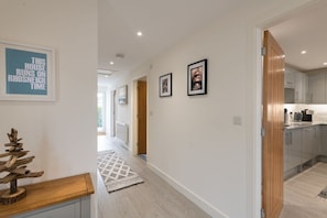A hallway with a wooden floor, a rug, and framed pictures on the wall.