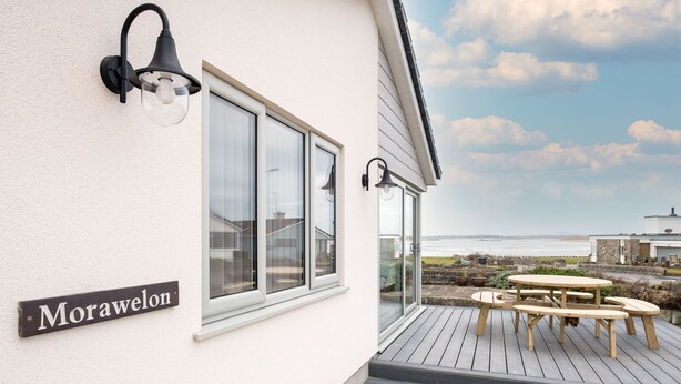A coastal property named Morawelon with a deck, outdoor seating, and a view of the sea.