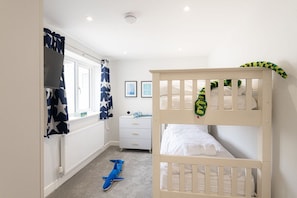 A child's bedroom with bunk beds, a dresser, and a window with star-patterned curtains. - Morawelon: 100m from the beach in Rhosneigr (Rhosneigr)
