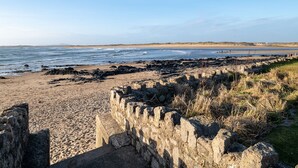 A coastal beach with a stone wall and rocky shoreline.