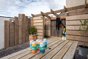 A wooden deck with a pergola, a potted plant, and a metal bucket.