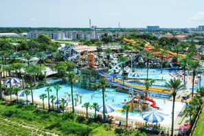 Un parc aquatique doté de plusieurs piscines, de toboggans et d’une grande piscine centrale entourée de palmiers.