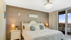 Ein Schlafzimmer mit einem großen Bett, Holzwandverkleidung, einer Chandelier und Blick ins Freie.