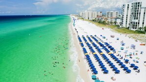 Ein Strand mit blauen Sonnenschirmen und weißem Sand.