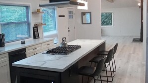 Una cocina moderna con una isla grande, armarios negros e iluminación colgante.