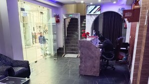A lobby with a reception desk, a sofa, and a staircase. - Dalton Hotels  (New Delhi)