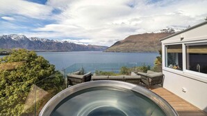 Et moderne hus med jacuzzi, udendørs siddeplads og udsigt til sø og bjerge.