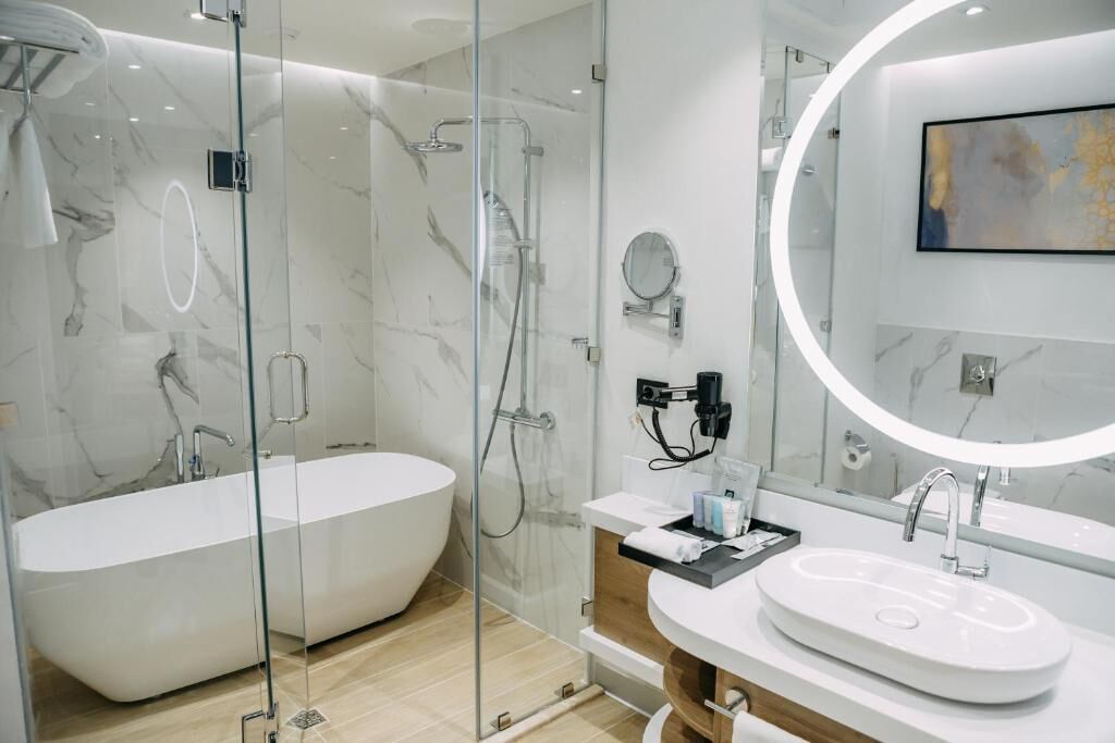 Un baño moderno con una bañera independiente, una ducha con cerramiento de vidrio y un lavabo con espejo.