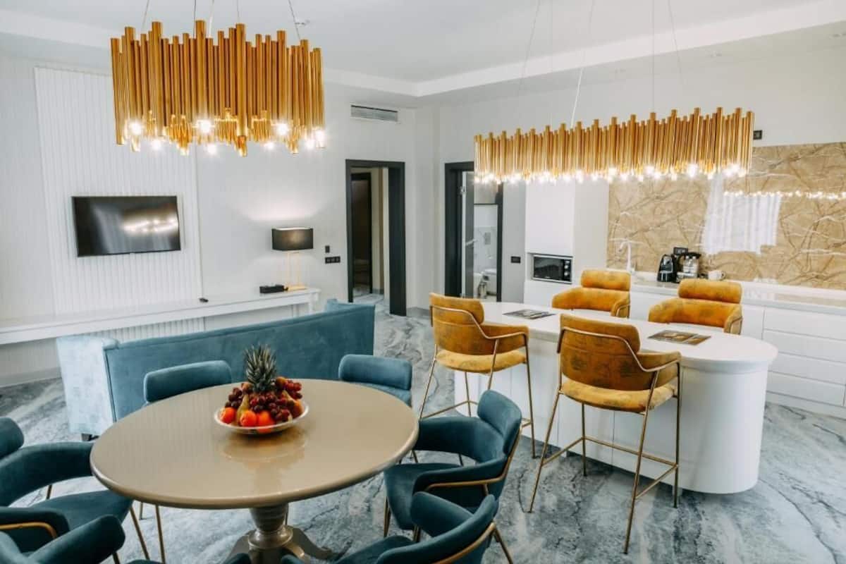 A modern dining area with a round table, blue chairs, and a fruit bowl.