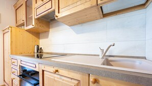 Een keuken met houten kastjes, een roestvrijstalen waterkoker en een moderne gootsteen.