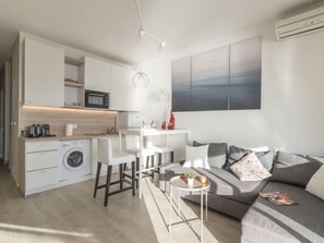 A compact living space with a kitchenette, a dining area, and a seating area with a sofa and chairs.