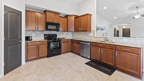 A modern kitchen with wooden cabinets, a black microwave, stainless steel appliances, and a tiled backsplash. - Peaceful Midland Cottage- Family & Pet Friendly, Near Golf, Parks, Nature Trail & Shopping! +15% Off (Midland)