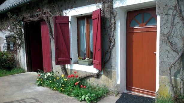 A house with a red door, a window with red shutters, and a small flower box on the porch. - Gîte "des coussieres" between peace and nature (Courteix)
