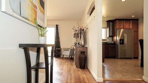 Una cocina moderna con armarios de madera, un refrigerador de acero inoxidable y una zona de comedor con una mesa y sillas.