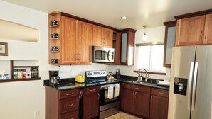 Una cocina moderna con armarios de madera oscura, electrodomésticos de acero inoxidable y piso de baldosas.