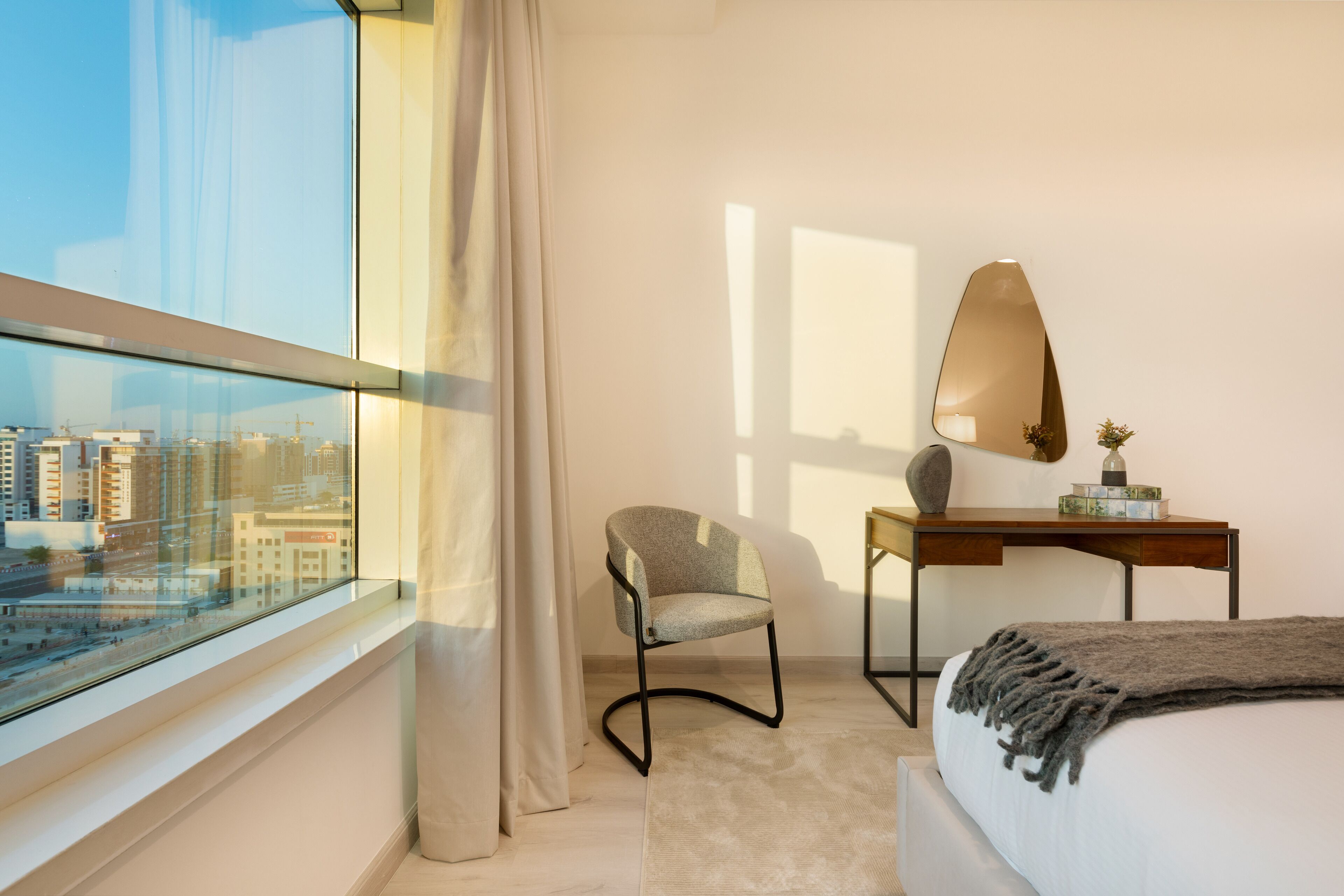 Une chambre d’hôtel moderne dotée d’une grande fenêtre, d’un bureau, d’une chaise et d’un lit.