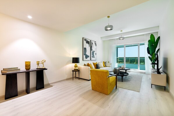 A modern living room with a sofa, a yellow armchair, a coffee table, and a console table with decorative items. - Maison Privee - Millennium Executive Tower (Dubai)