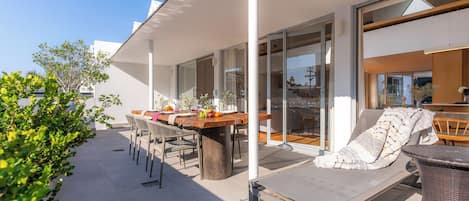 A modern outdoor patio with a dining table, chairs, and a lounge area.