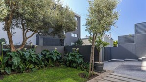 Un quartier résidentiel moderne doté d’une pelouse bien entretenue, d’une allée pavée et d’une entrée sécurisée par un portail.