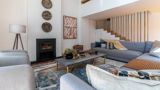 Un salon moderne avec une cheminée, un canapé, une table basse et un escalier.