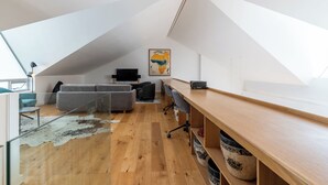 Ein modernes Loft mit schrägem Dach, einem Holztisch, einem grauen Sofa und einer großen Karte an der Wand.