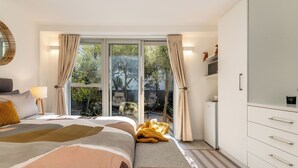 Ein modernes Schlafzimmer mit einem großen Bett, einer Couch, einem Schreibtisch und einem Kleiderschrank.