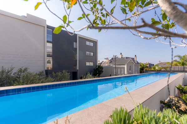 Un edificio moderno con piscina, rodeado de vegetación.