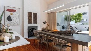 Une cuisine moderne dotée d’un îlot central, de planchers en bois et offrant une vue sur l’extérieur grâce à de grandes fenêtres.