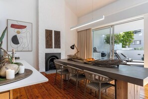 Een moderne keuken met een centraal eiland, houten vloeren en een uitzicht op de omgeving door grote ramen.