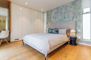 A bedroom with a large bed, a bedside lamp, a chair, and a wardrobe.