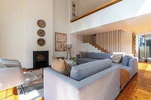 Ein modernes Wohnzimmer mit Kamin, Treppe und einem großen grauen Sofa.