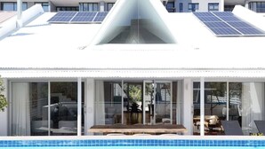 Un bâtiment moderne doté d’une piscine, de grandes fenêtres et de panneaux solaires sur le toit.