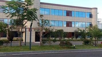 A modern building with a flat roof, multiple windows, and a gated entrance.