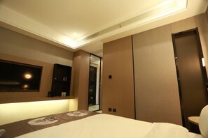 A hotel room with a bed, a large mirror, and a wardrobe.
