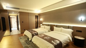 Ein Hotelzimmer mit zwei Betten, einem großen Spiegel, Holzboden und einem kleinen runden Tisch.