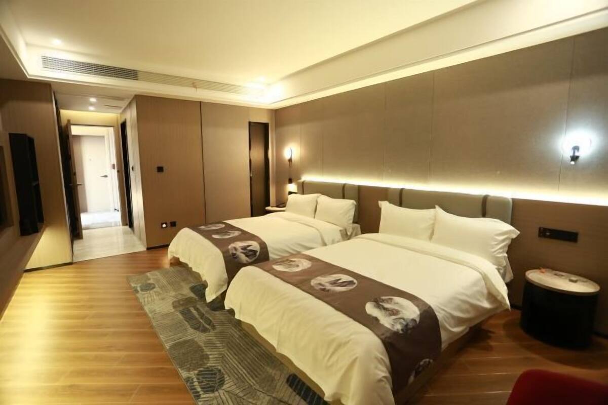 A hotel room with two beds, a large mirror, a wooden floor, and a small round table.