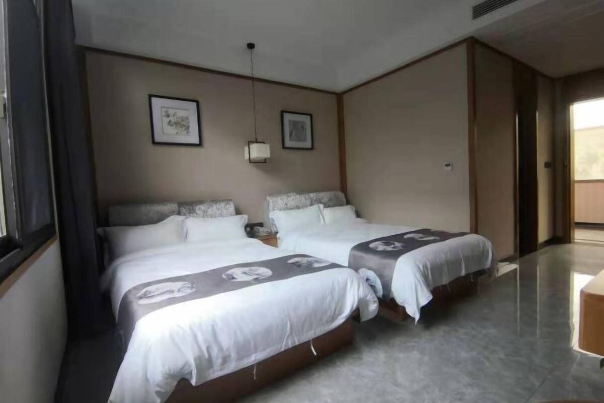 A hotel room with two beds, a small table, and a window.