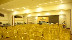 Un salón de conferencias con filas de sillas amarillas, un escenario con un cartel que dice 'Retailer Meet 2023' y una exhibición de productos sobre mesas.