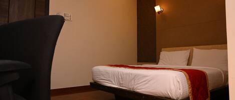 A bedroom with a bed, a chair, and a wall-mounted light fixture.