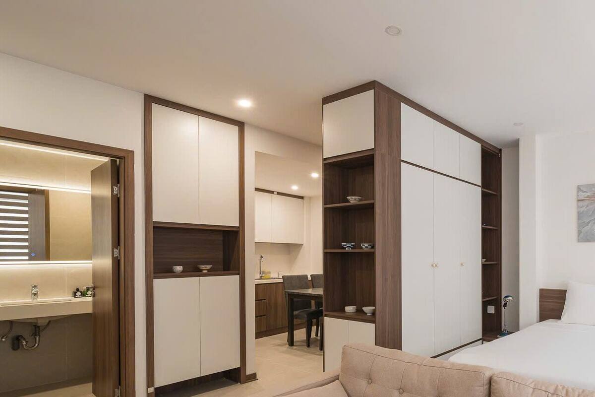 A modern hotel room with a bed, a desk, and a wardrobe.