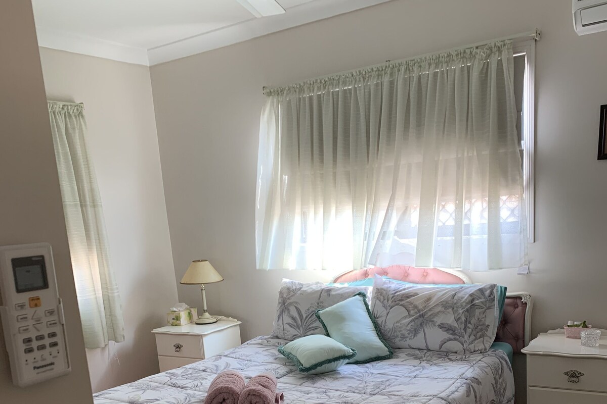 A neatly arranged bedroom with a bed, bedside tables, a lamp, and a ceiling fan.