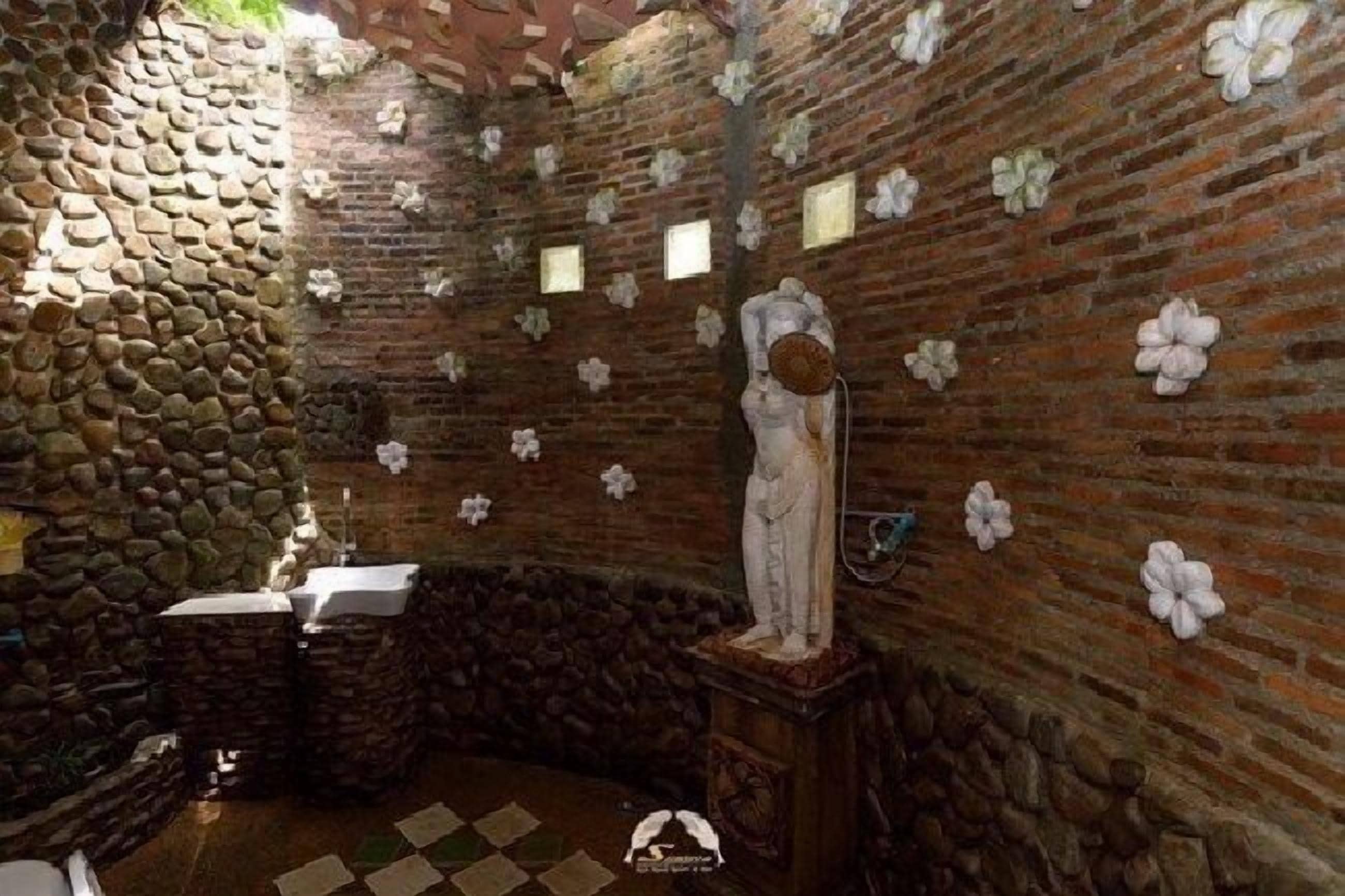 A stone-walled room with a statue, a sink, and a checkered floor.