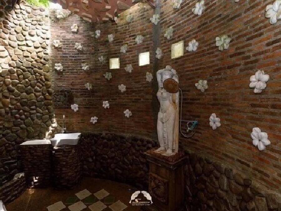 A stone-walled room with a statue, a sink, and a checkered floor.