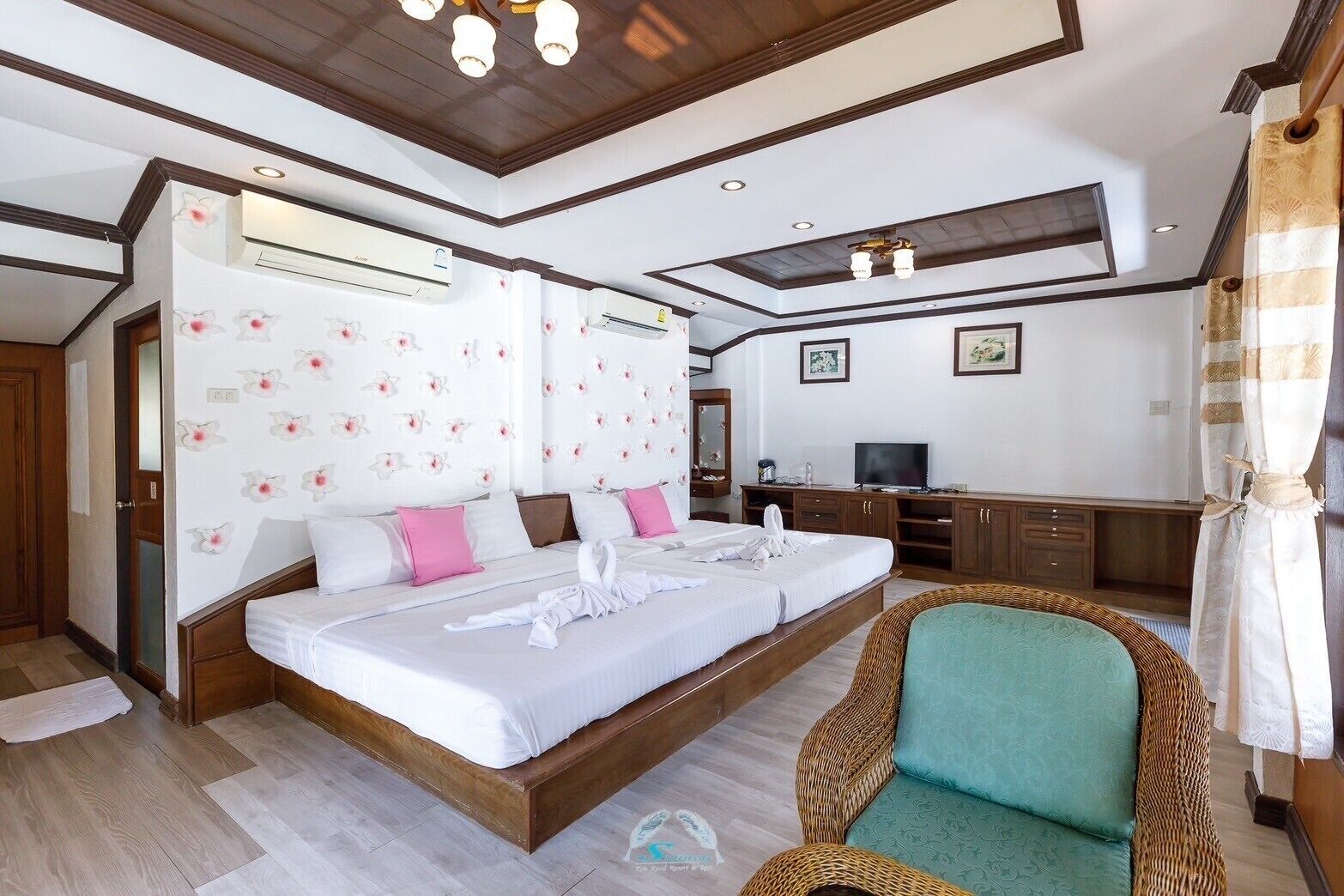 Una camera d'albergo con un letto grande, una televisione e una poltrona in vimini.